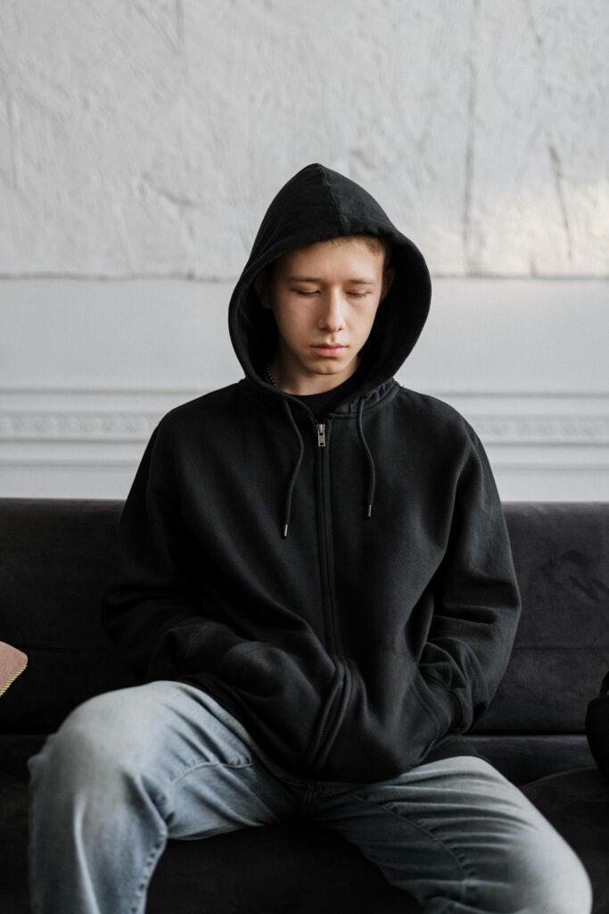 Man in Black Hoodie Sitting on Brown Couch